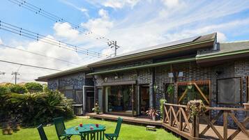 Een modern huis met een bakstenen gevel, grote glasramen en een houten terras.
