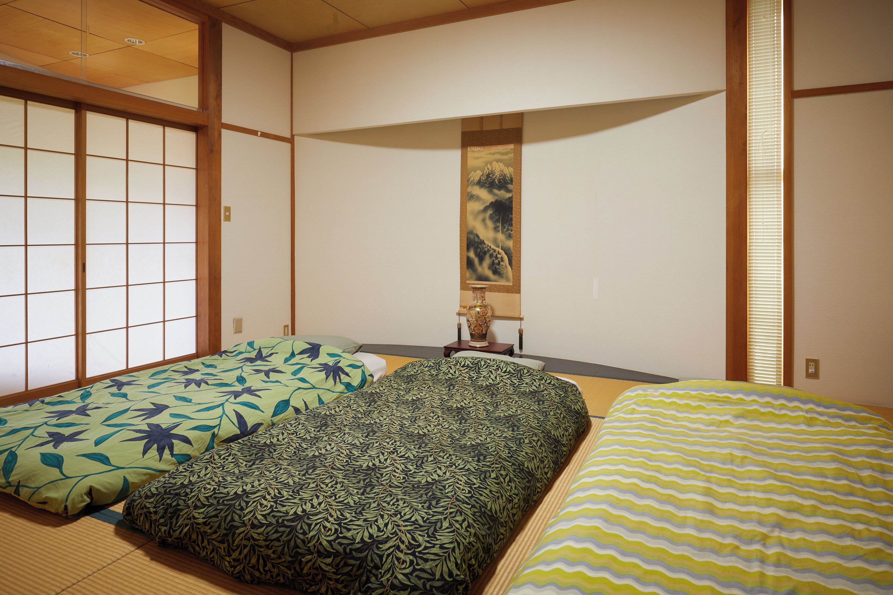 Een traditionele Japanse kamer met tatami vloeren, een shoji scherm en een futon bed met beddengoed met een patroon.