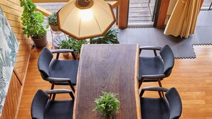 A dining area with a wooden table and six chairs, a hanging light fixture, and potted plants. - Entire house reserved, spacious living,  bath in Hiba trees, BBQ, Foliage plants (Isumi, Oharadai)