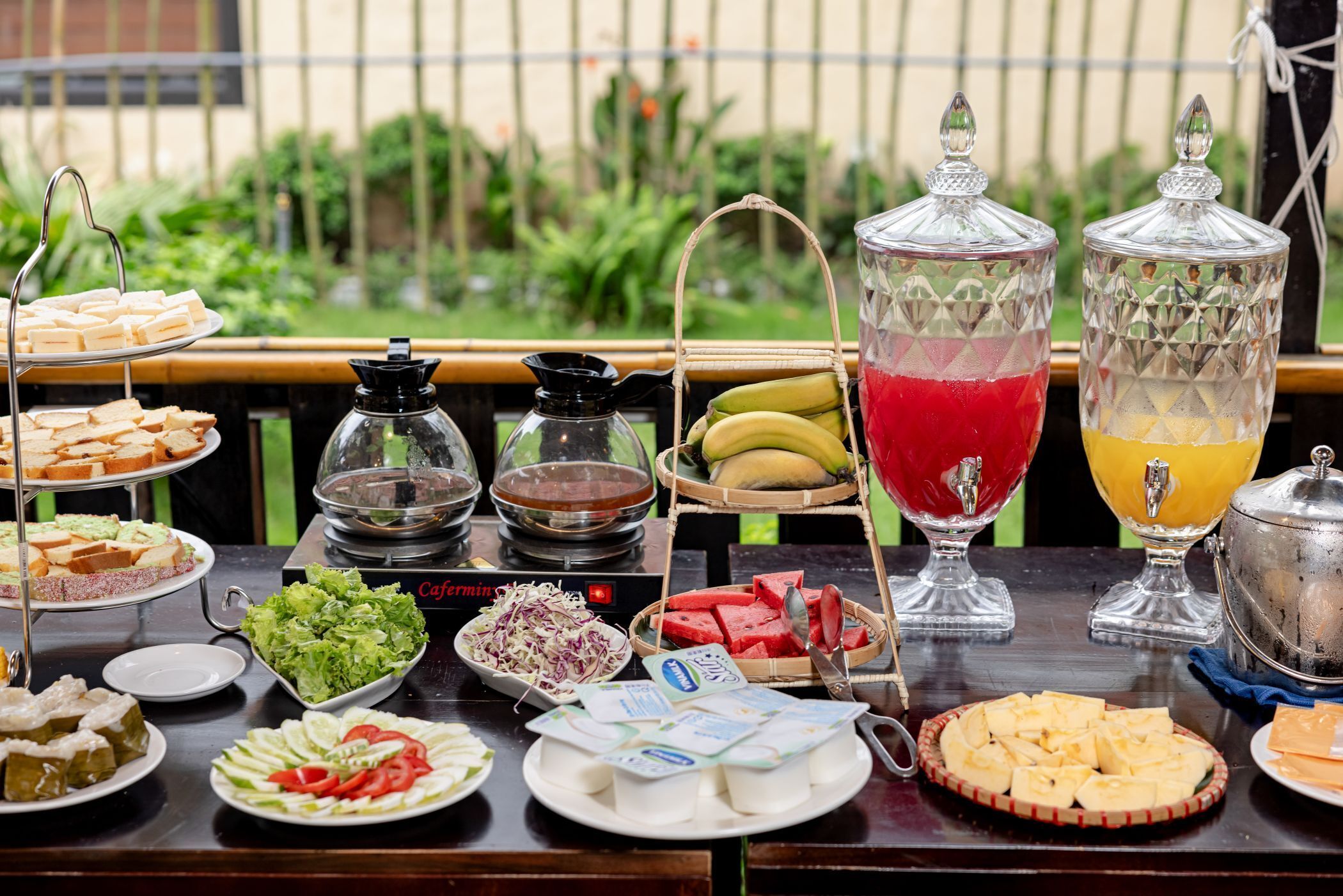 A buffet table with various food items and beverages, including sandwiches, salads, and fruit.