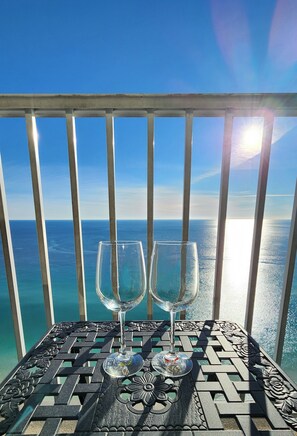 Un balcon avec une balustrade en métal et une table avec deux verres à vin.