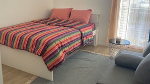 Ein Schlafzimmer mit einem Bett, einem kleinen runden Tisch mit Kerze und einem grauen Sofa.