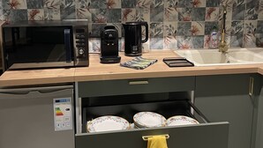 Eine Küche mit einer Mikrowelle, einer Kaffeemaschine und einer Schublade mit Tellern.