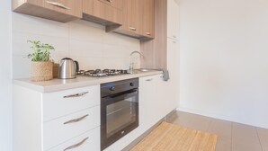 A modern kitchen with wooden cabinets, a stainless steel stove, and a built-in oven. - Ponente Balcony Garden (Gravedona)
