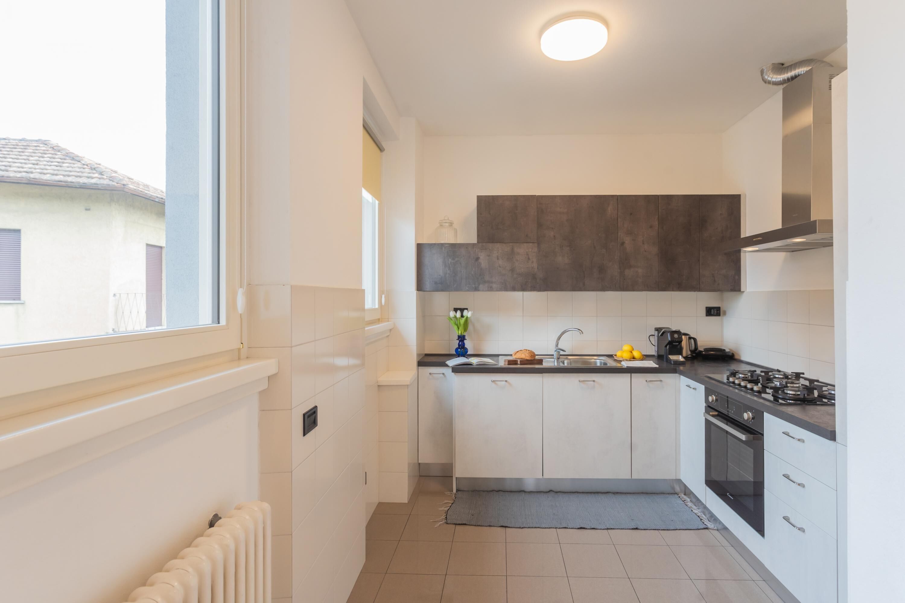 A modern kitchen with white cabinets, a built-in stove, and a window providing natural light.