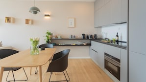 Een moderne keuken met een houten eettafel, zwarte stoelen en een hanglamp.