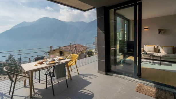 Een balkon met een eettafel, een bank en uitzicht op bergen.