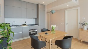 Een moderne keuken met grijze kastjes, een houten eettafel en zwarte stoelen.