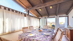 A dining area with a table set for two, wooden chairs, a floral tablecloth, and a view of the outdoors. - Bilo Porto Rotondo Castello 3 (Olbia)