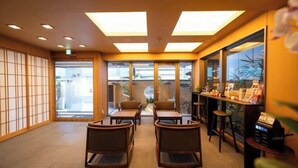 Une pièce de style japonais traditionnel, avec un sol recouvert de tatamis, des paravents en papier de riz (shoji) et un comptoir d’accueil où sont disposées des brochures.