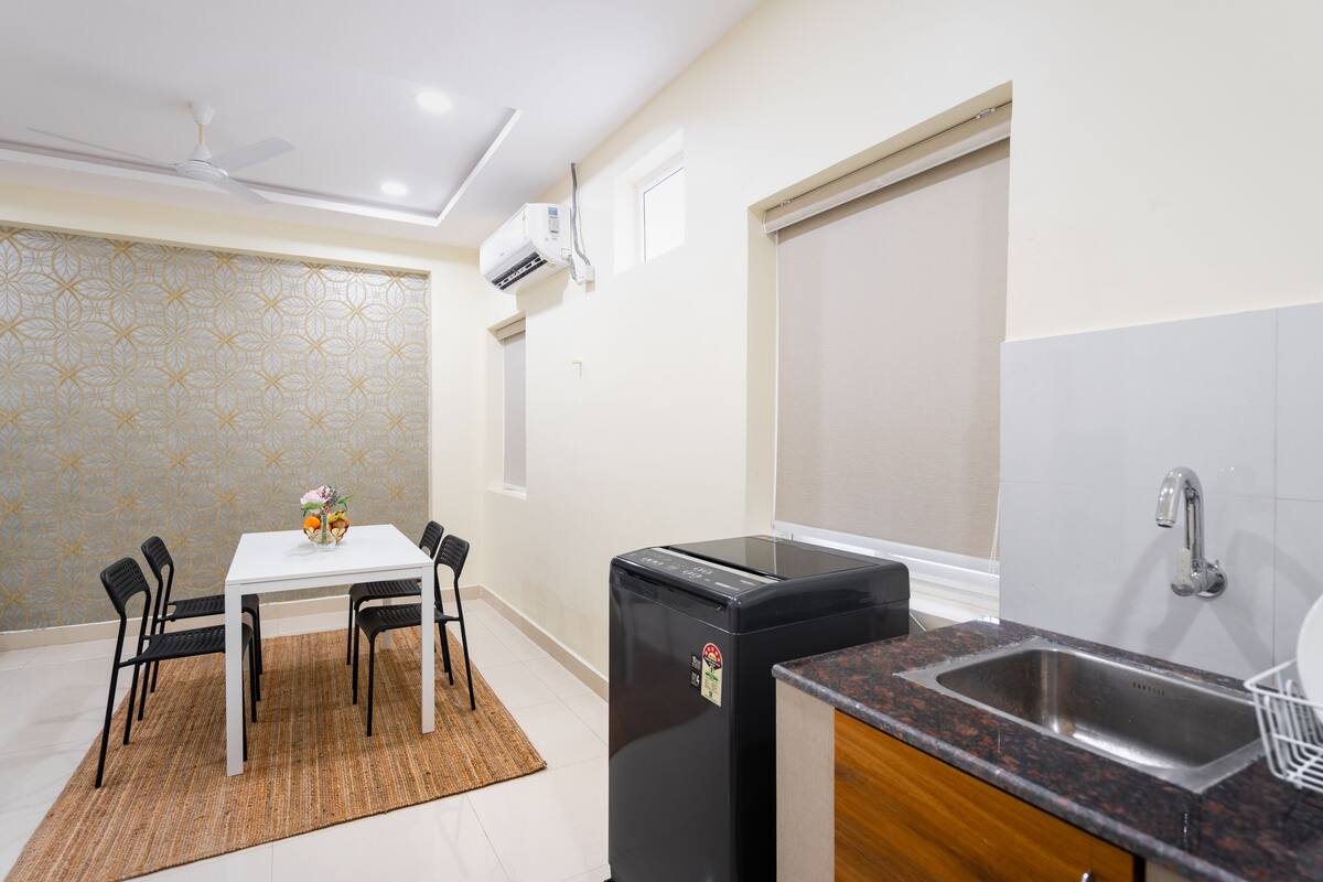 A compact kitchen with a refrigerator, sink, and a dining area with chairs and a table.