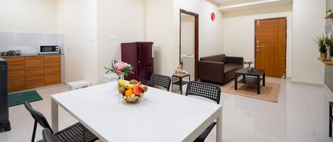 A modern living room with a dining table, chairs, a sofa, and a coffee table. There is a microwave in the kitchen area.