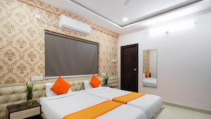 A hotel room with a large bed, two nightstands, a potted plant, an air conditioning unit, and a mirror on the wall. - Iris At Nest (Hyderabad)