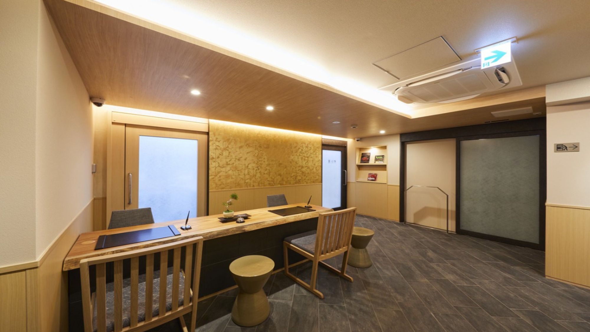 A conference room with a long table, chairs, and a small stool. There are two doors, one with a frosted glass panel and another with a solid panel.