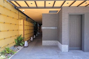 L’entrée de l’hôtel Kyoto Gion se distingue par son design moderne, avec un mur en bambou et un chemin dégagé menant à l’entrée.