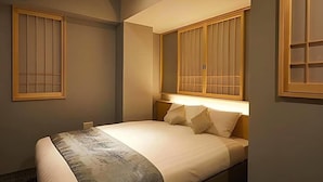A bedroom with a bed, a nightstand, and a window with a wooden frame. - Kyoto Gion Hotel (Kyoto)