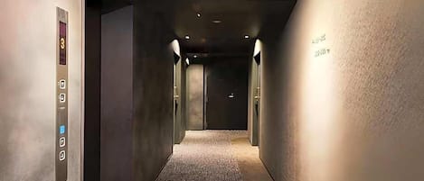 A hallway with an elevator, a security camera, and a wall with a sign.