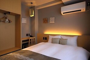 A hotel room with a large bed, a desk, a chair, an air conditioner, and wall-mounted artwork. - Kyoto Gion Hotel (Kyoto)