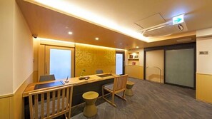A conference room with a long table, chairs, and a small stool. There is a door with frosted glass panels and a wall-mounted shelf with framed pictures. - Kyoto Gion Hotel (Kyoto)
