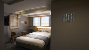 Een hotelkamer met een bed, een stoel, een klein tafeltje, een raam met zonwering en een aan de muur hangend kunstwerk.