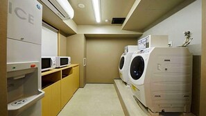 A laundry room with a washing machine and dryer, a microwave, and a water dispenser. - Kyoto Gion Hotel (Kyoto)