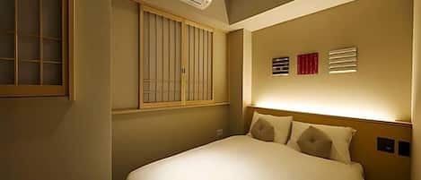 Ein Hotelzimmer mit Bett, Fenster mit Jalousien, Klimaanlage und einem Wandbild.