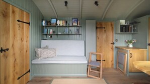 Ein gemütliches Zimmer mit einer Holzbank, einem kleinen Holzstuhl, einem Bücherregal und einem Schrank.