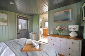 Ein Schlafzimmer mit einem Bett, einer Holzkommode, einem Spiegel und einem Tablett mit Tassen.