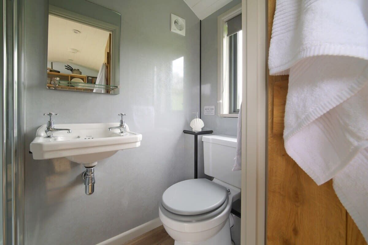 Une salle de bain avec un lavabo blanc, des toilettes, un miroir et une fenêtre.