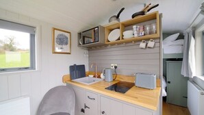 A compact kitchen with a sink, toaster, and shelves above the counter. - Charming Hut with Outdoor Bath & Decking, Sea Views (Sidmouth)