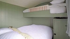 A bunk bed with white bedding, a green wall, and a cabinet with a towel hanging on it. - Charming Hut with Outdoor Bath & Decking, Sea Views (Sidmouth)