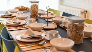 Una mesa de comedor preparada con varios cuencos, platos y tazas, junto con un frasco de aperitivos.