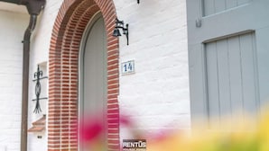 Un edificio blanco con un arco de ladrillo rojo y un letrero con el número 14.