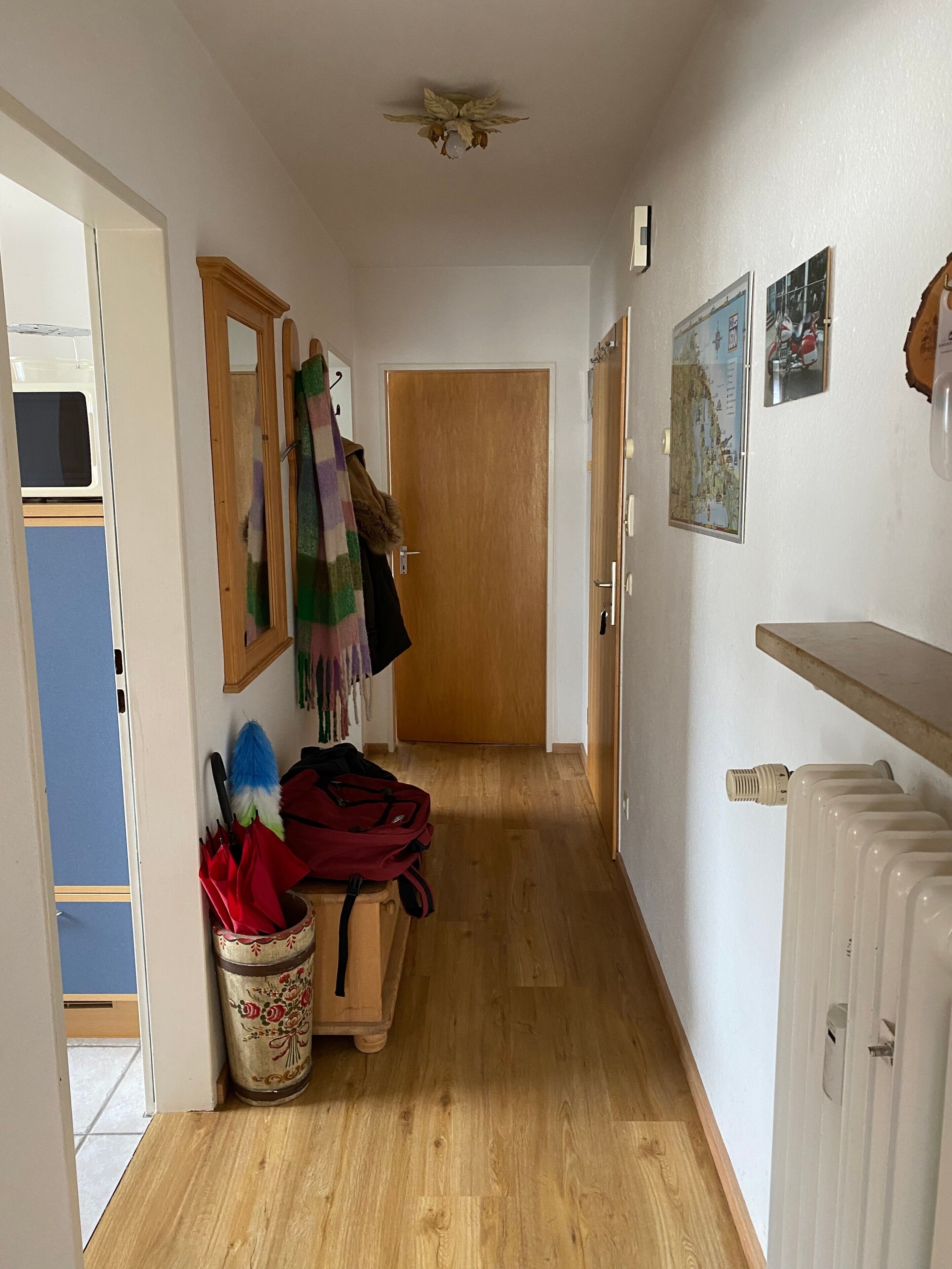 A hallway with a wooden door, a radiator, and a wall-mounted map.