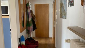 A hallway with a wooden door, a radiator, and a wall-mounted map. - Apartment 'Mountain View in Mittenwald' with Balcony, Wi-Fi & Alpine Views (Mittenwald)