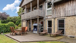 Een houten gebouw met balkon, terras en een tuin.