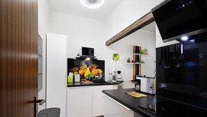 Une cuisine compacte équipée d’un four à micro-ondes, d’une cuisinière et d’une décoration murale sur le thème des fruits.