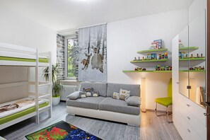 A child's room with bunk beds, a sofa, a chair, a radiator, a window with a view, and shelves with toys. - Apartment 'Die Käuzchenkuhle' with Mountain View, Private Terrace and Wi-Fi (Bad Sachsa)