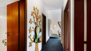 A hallway with a wooden door, a wall-mounted tree decoration, a white chair, and a blue carpet. - Apartment 'Der Falkenhorst' with Mountain View, Shared Terrace and Wi-Fi (Bad Sachsa)