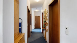 A hallway with wooden doors, a blue carpet, and a wall-mounted decoration. - Apartment 'Der Falkenhorst' with Mountain View, Shared Terrace and Wi-Fi (Bad Sachsa)
