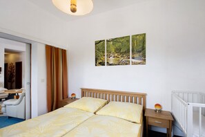 Ett sovrum med en säng, ett nattduksbord, en lampa, en stol och en tavla på väggen.