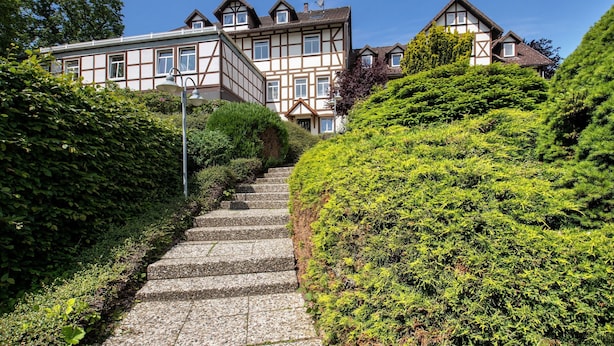 A stone staircase leading up to a traditional building with a symmetrical facade and multiple windows. - Apartment 'Der Falkenhorst' with Mountain View, Shared Terrace and Wi-Fi (Bad Sachsa)