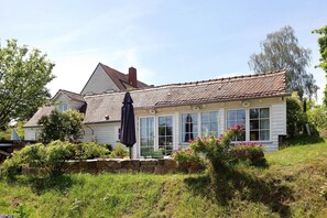 A house with a sloped roof, large windows, and a stone wall in front. - Holiday Home 'Gästehaus Altes Forstamt Sinntal' with Mountain View, Terrace and Wi-Fi (Sinntal)