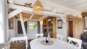 A dining area with a round table, white chairs, a woven placemat, and a hanging light fixture. - Holiday Home 'Gästehaus Altes Forstamt Sinntal' with Mountain View, Terrace and Wi-Fi (Sinntal)