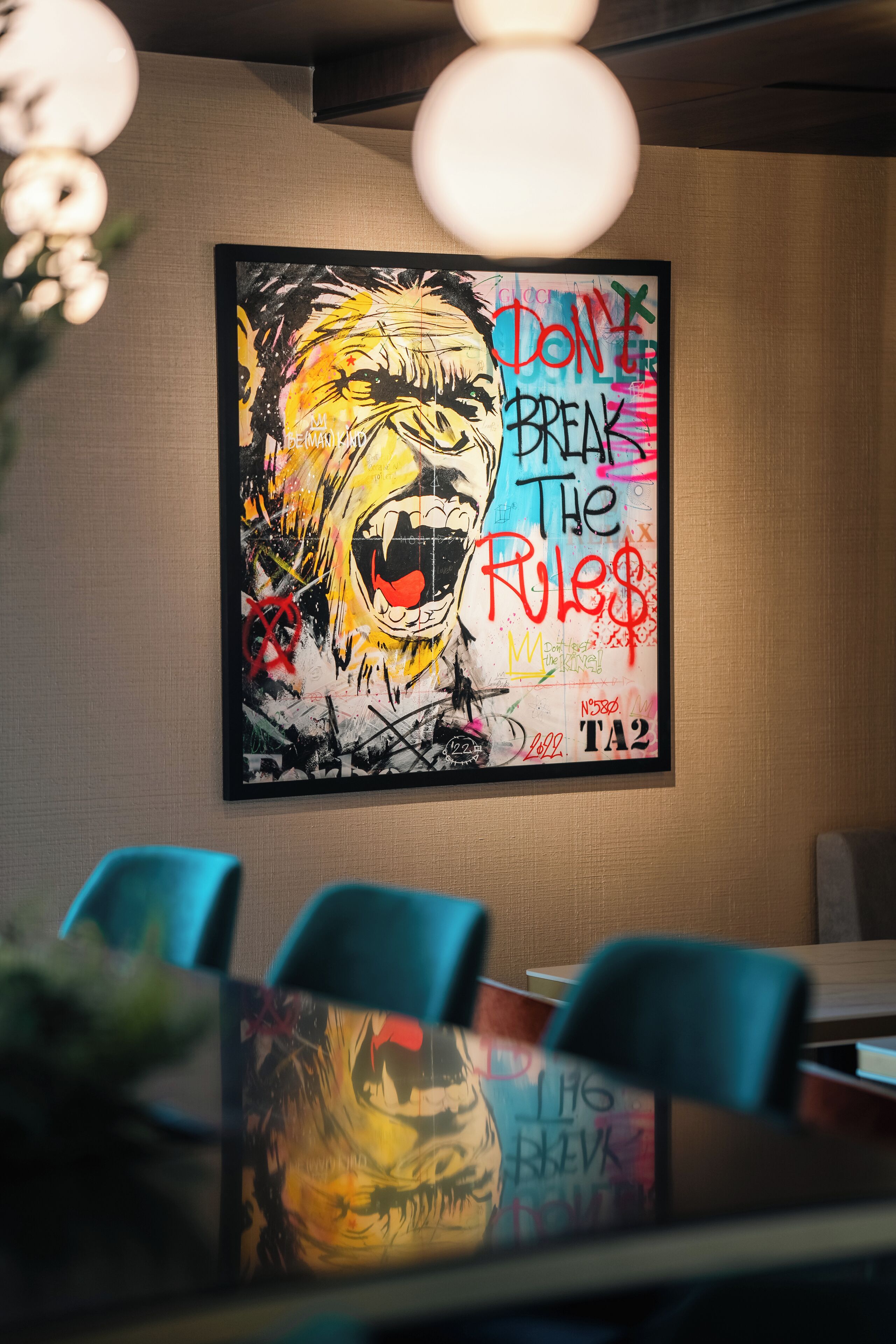 Un salón de conferencias con un cuadro abstracto grande en la pared, una mesa con sillas y una lámpara de techo.