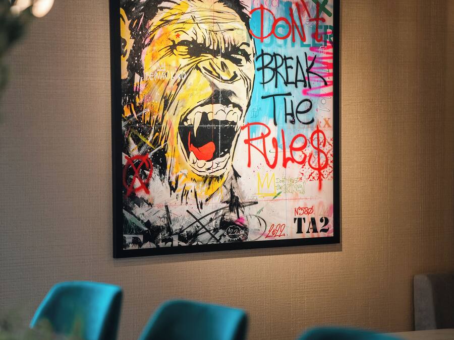 Un salón de conferencias con un cuadro abstracto grande en la pared, una mesa con sillas y una lámpara de techo.