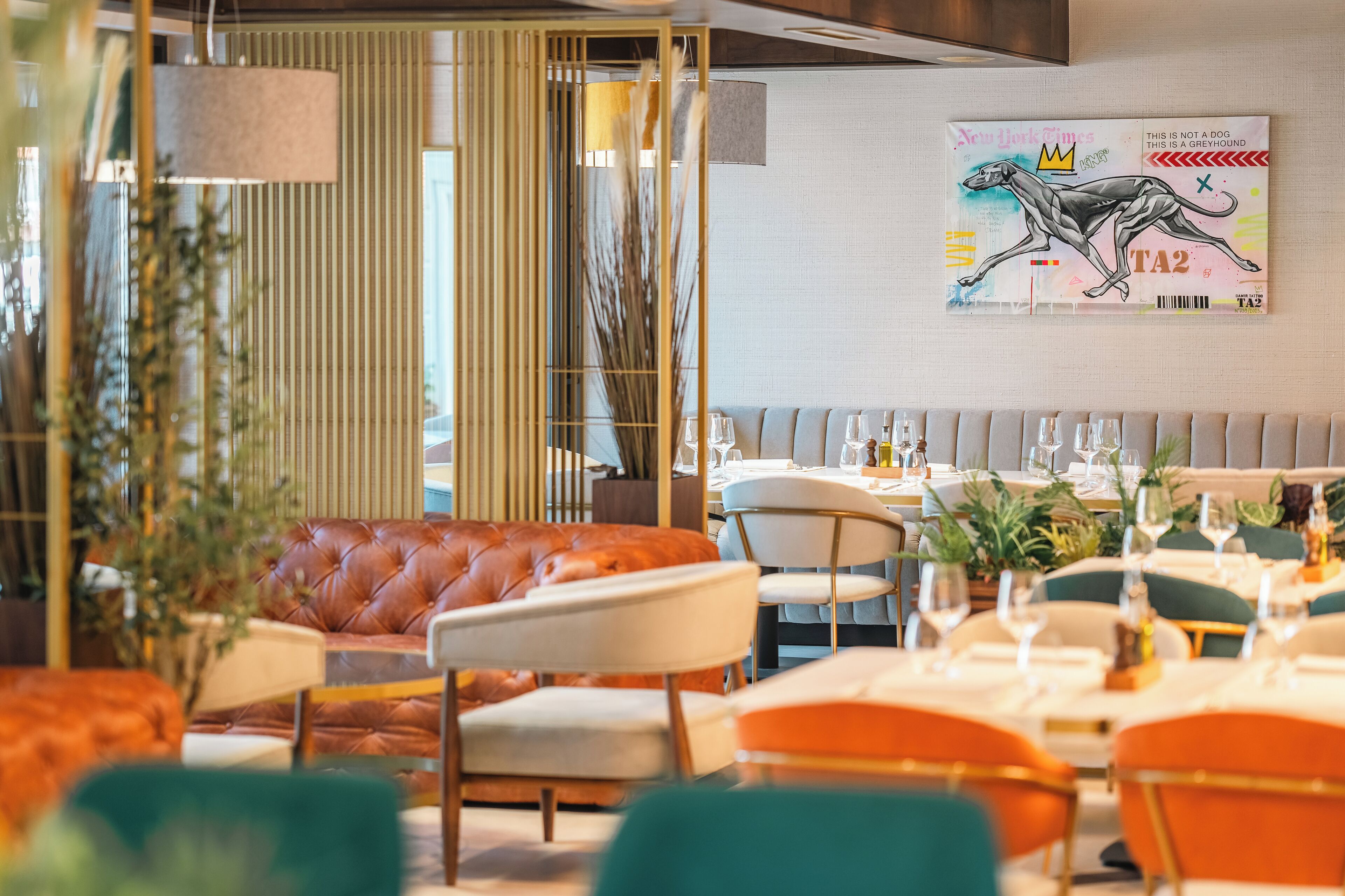 A restaurant with a modern interior, featuring leather seating, white and orange chairs, and a wall-mounted menu.