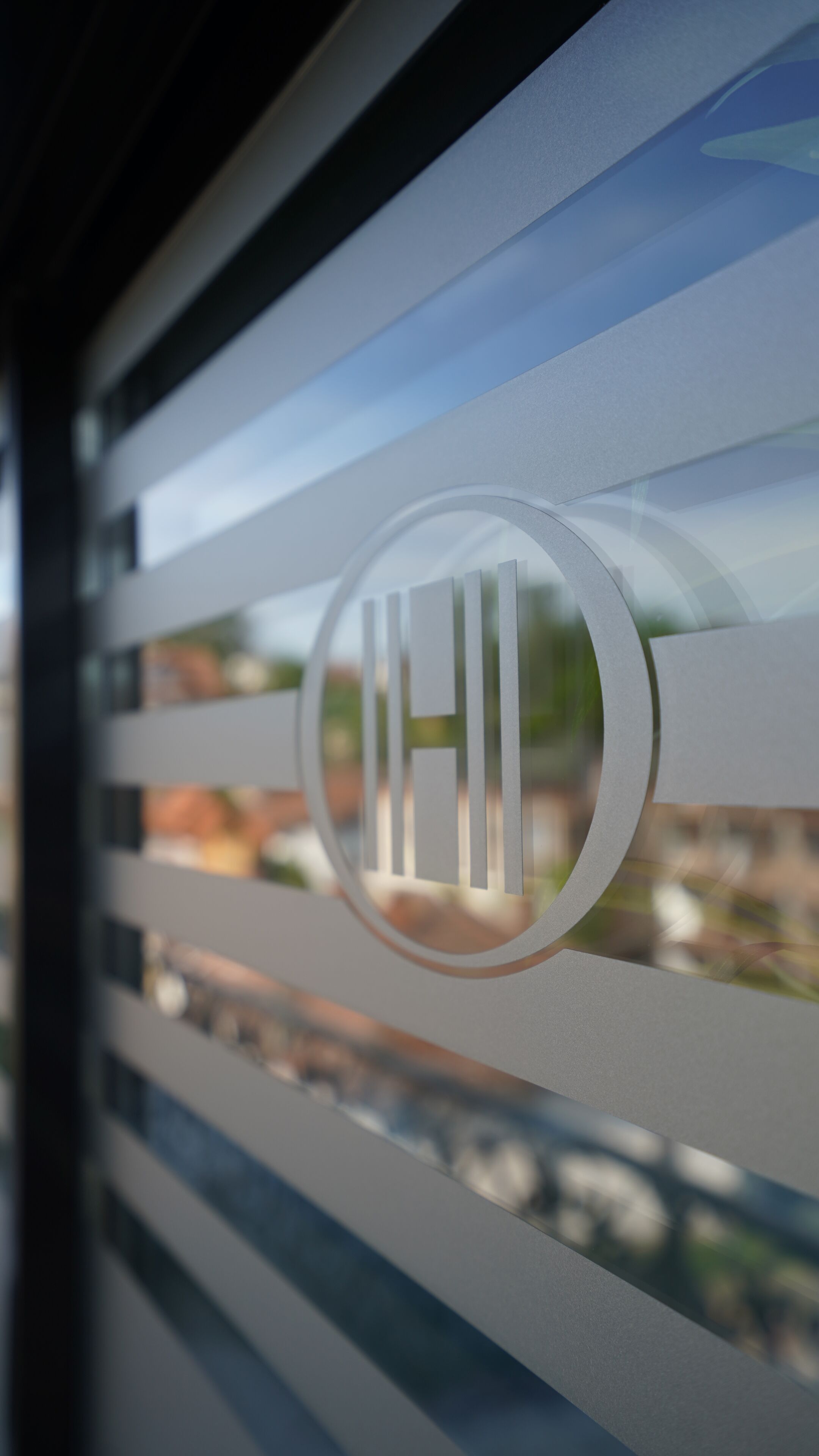Een raam met horizontale luiken en een rond logo.