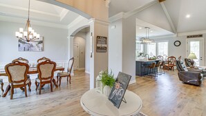 Un salon spacieux avec une table ronde, un lustre et un coin repas avec des chaises en bois.