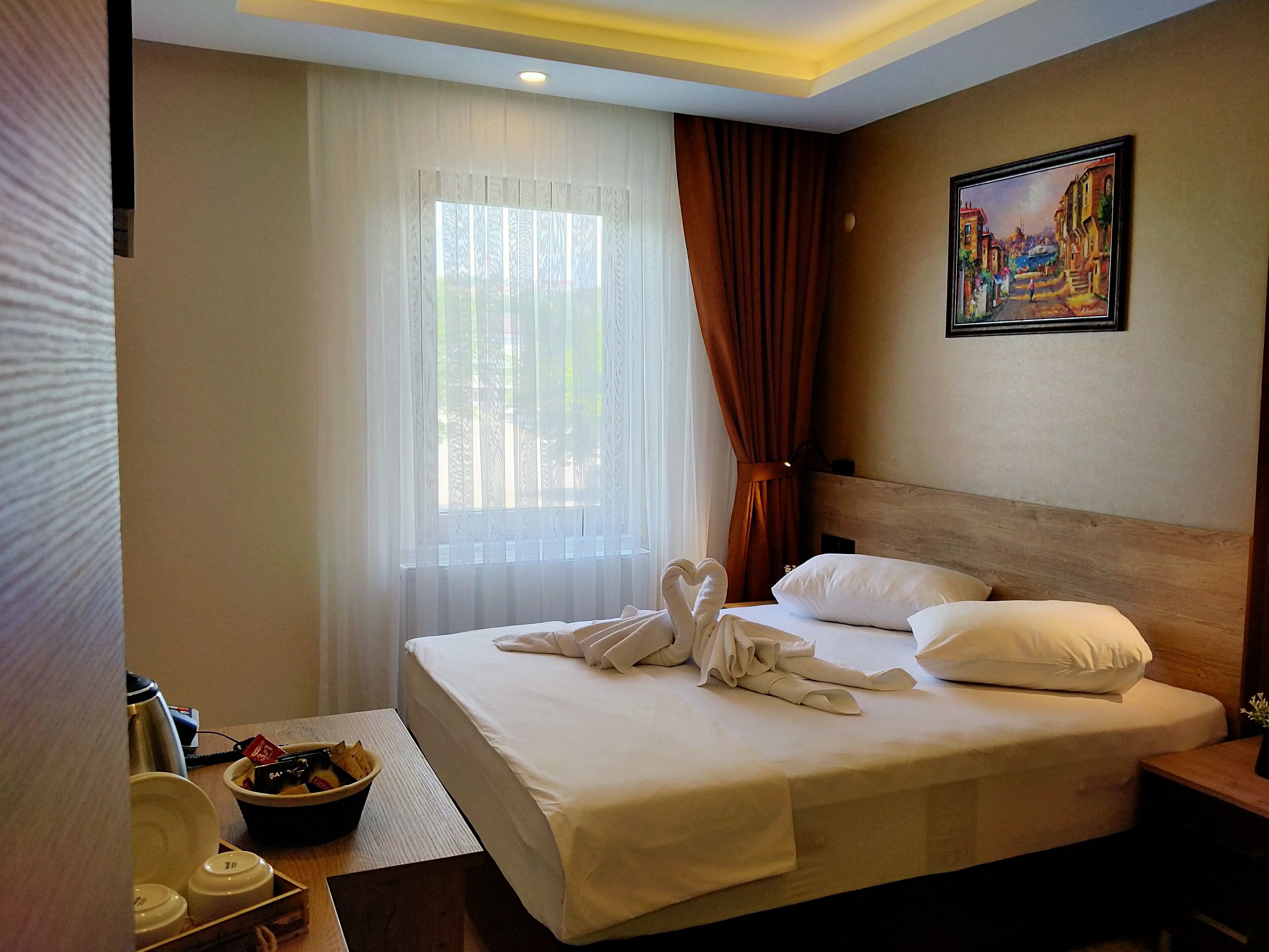 Una habitación de hotel con una cama bien hecha, un cuadro en la pared y una ventana con cortinas.